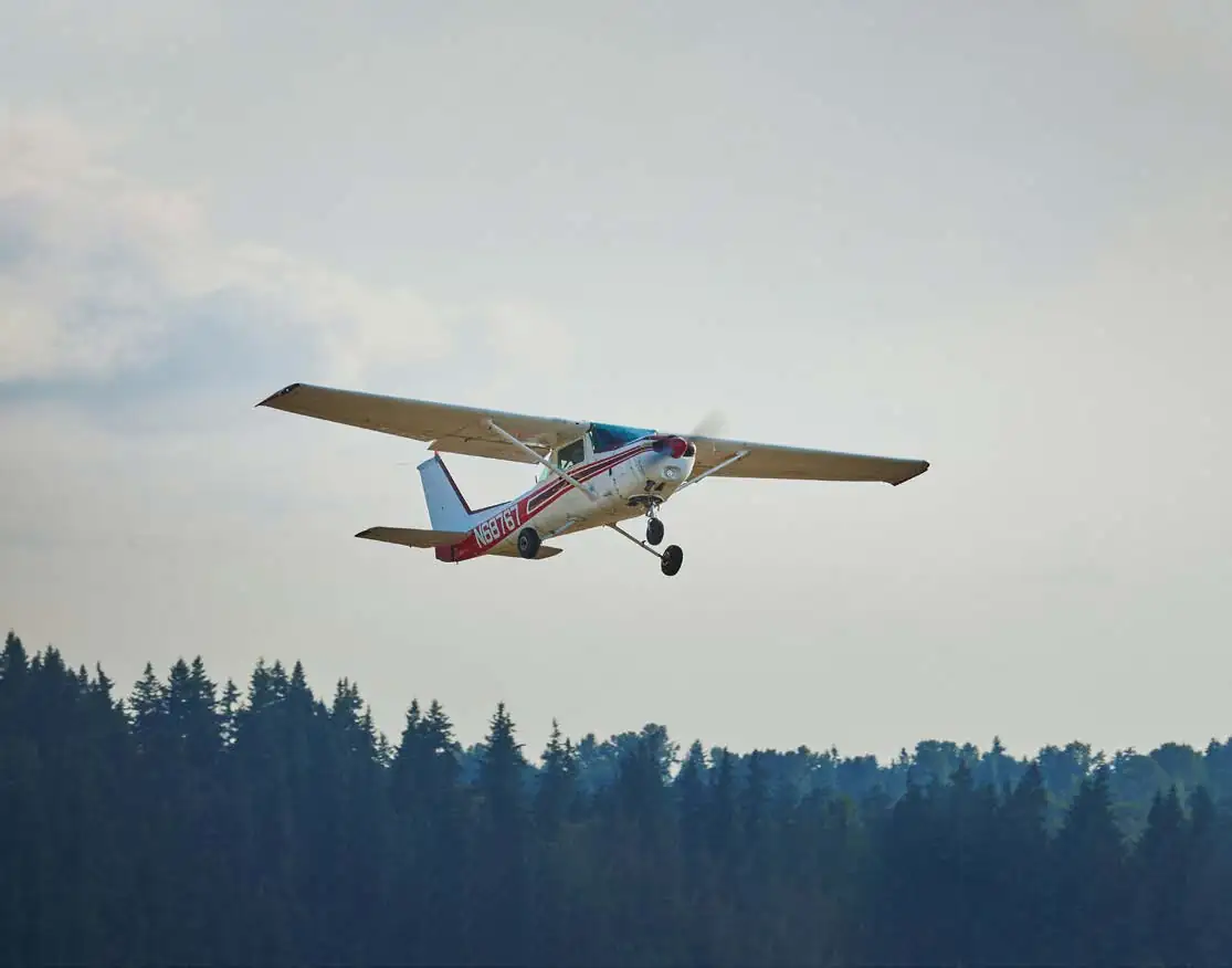 Cessna in flight over a forest