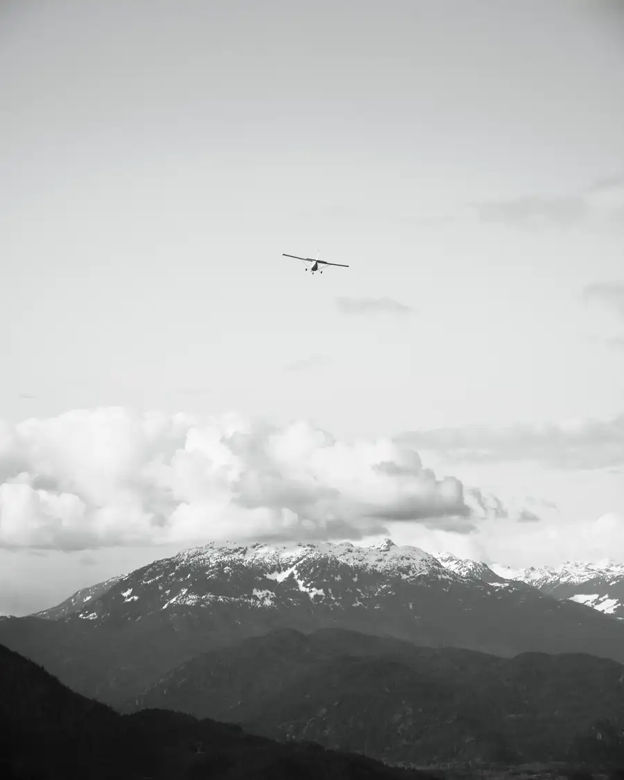 Airplane flying above clouds and snowy mountains